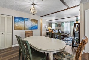A dining area with a white table and chairs, a ceiling fan, and artwork on the wall.