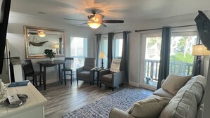 A spacious living area with a ceiling fan, a dining table with chairs, a sofa, and a view of the outdoors through large windows. - Beautiful gated community,  (Panama City)