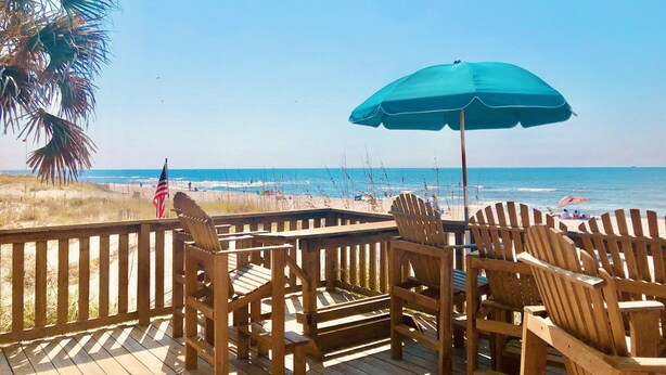 A wooden deck with chairs and an umbrella overlooking a beach. - Beautiful gated community,  (Panama City)