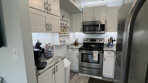 A modern kitchen with white cabinets, stainless steel appliances, and a black countertop. - Beautiful gated community,  (Panama City)