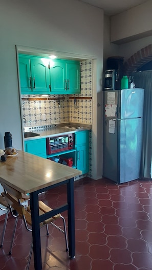 A kitchen with teal cabinets, a red toaster oven, and a blue refrigerator.