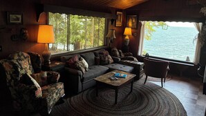 Un salon chaleureux avec un canapé, des fauteuils, une table basse et une vue sur l’eau.