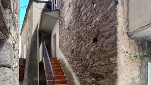Eine enge Steintreppe führt zu einem Gebäude mit einer Steinmauer.