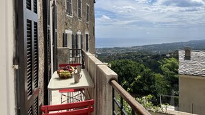 Ein Balkon mit Tisch für zwei Personen, einem Stuhl und einer Obstschale.