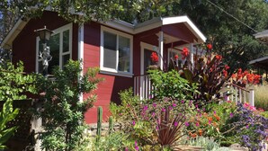 A red house with a porch, surrounded by various plants and flowers. - ~AMITABHA~ Wine Country Cottage! Perfectly Located in Santa Rosa (Santa Rosa)