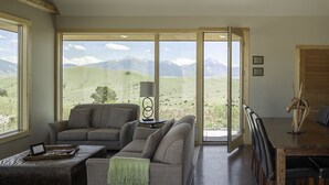 A living room with a large sliding glass door leading to a mountain view, a sofa, a coffee table, and a lamp.