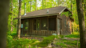 A rustic cabin with a chimney, large windows, and a porch.