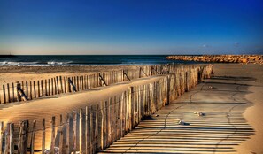 A wooden boardwalk leading to a beach with a clear view of the ocean and rocky shoreline.