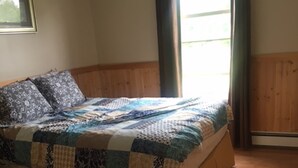 Une chambre à coucher avec un cadre de lit en bois, une couvre-lit matelassée et une fenêtre avec des rideaux.