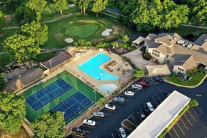 Vue aérienne d’un quartier résidentiel avec une piscine, des courts de tennis et un parcours de golf.