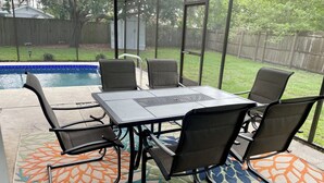 Een terras buiten met een pooltafel, stoelen en een kamerkleed met een patroon.