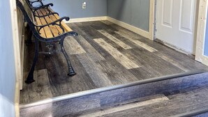 A hallway with a bench, a door with a sign, and a built-in shelf unit.