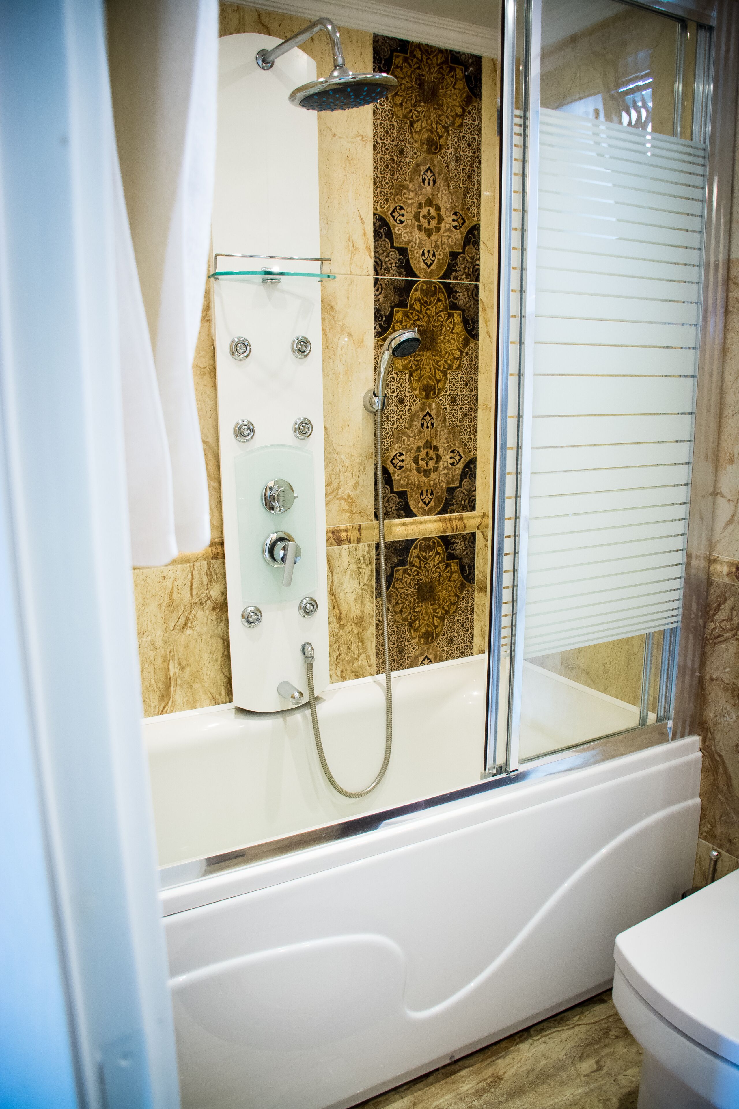 Un baño moderno con ducha de vidrio, una bañera blanca y un inodoro.