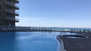 En swimmingpool med havudsigt, omgivet af et hegn og liggestole.