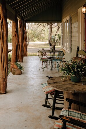 Une terrasse couverte, aménagée avec des meubles en bois rustique, une table à manger et des chaises.