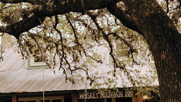 A rustic building with a sign reading "Whiskey Mountain Inn".
