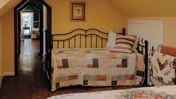 Un dormitorio con dos camas, suelo de madera, un cuadro en la pared y un pasillo que conduce a otra habitación.
