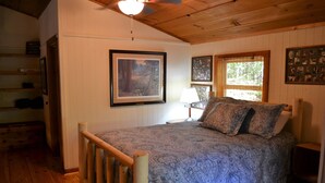 A bedroom with a wooden bed, a framed picture on the wall, and a window with blinds.