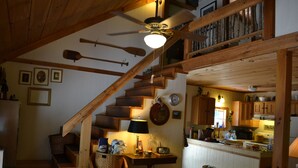 A rustic interior with a wooden staircase, a dining area, and a kitchen.