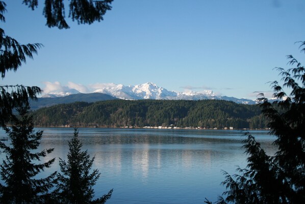Un lac paisible, bordé d’une forêt, avec des montagnes enneigées qui se dressent à l’horizon.