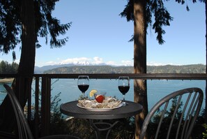 Une table avec deux verres de vin rouge, une tranche de citron et une assiette d’huîtres.