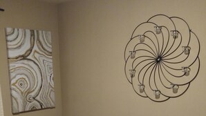 Un dormitori amb un llit, roba de llit amb ratlles i una decoració mural.