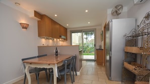 Een moderne keuken met een houten tafel en stoelen, een koelkast en een ventilator aan de muur.