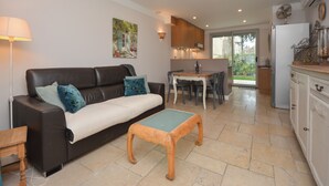 Een moderne woonkamer met een bank, een salontafel en een eethoek met een tafel en stoelen.