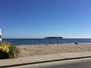 A beach with a clear view of the ocean and a distant island.
