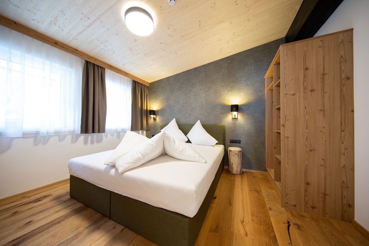 Un dormitorio moderno con una cama grande, suelo de madera, techo inclinado y estanterías empotradas de madera.