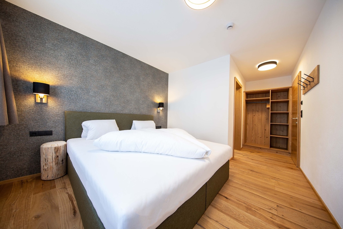 Un dormitorio moderno con una cama grande, suelo de madera y un armario empotrado.