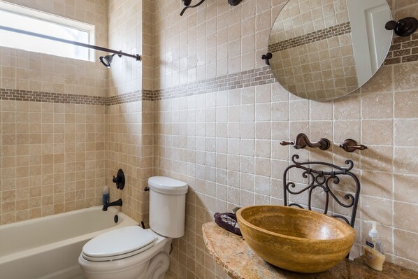 A bathroom with a bathtub, toilet, and a large wooden basin on a countertop.