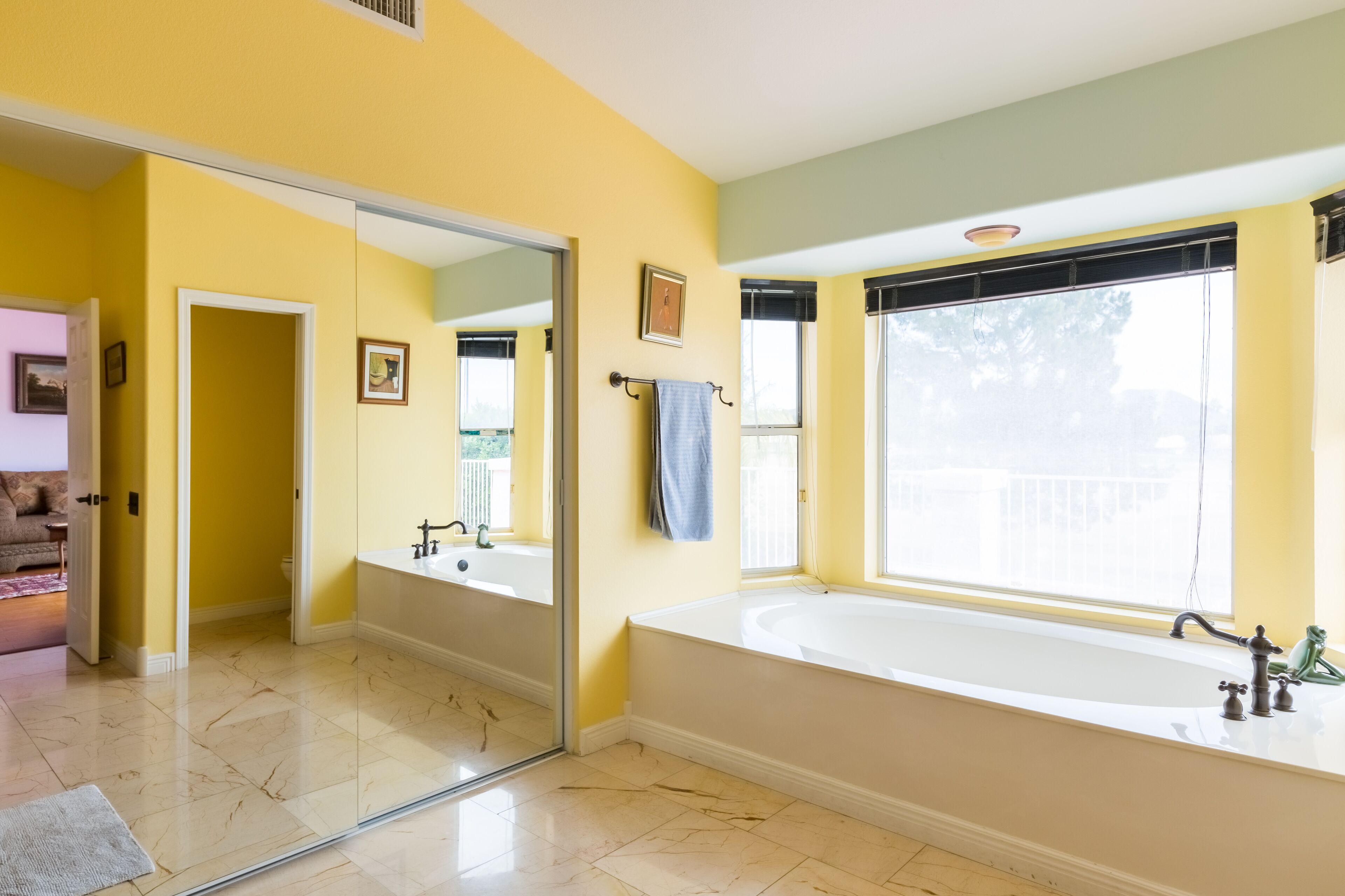 Un baño con un espejo grande, una bañera y un ventanal.