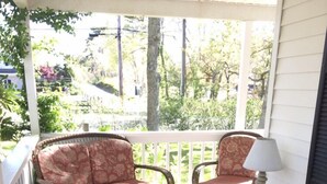 A covered porch with wicker furniture, a small table, and a lamp. - Charming Edgartown home with wrap around porch (Edgartown)