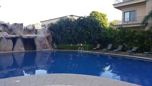 En pool med en klippformation och solstolar.