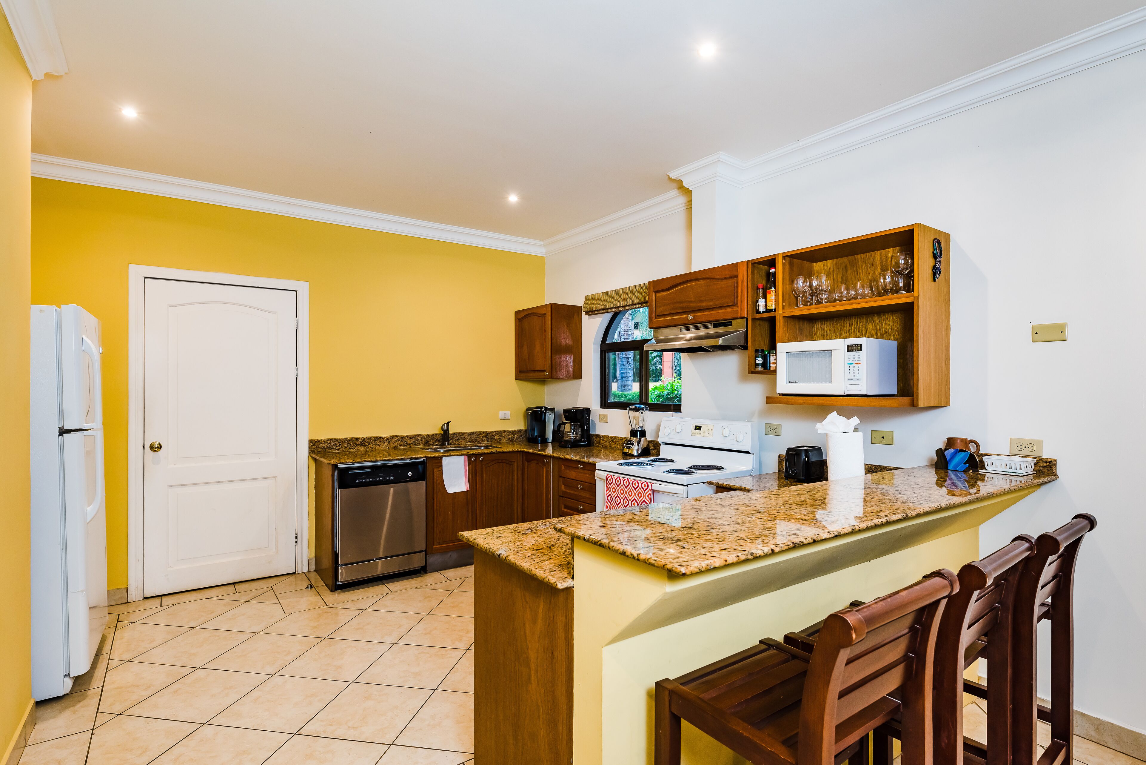 A compact kitchen with a central island, wooden cabinets, and a microwave.