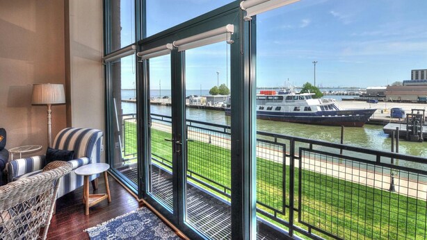 A balcony with large windows overlooking a marina with boats. - Upgrade Your Stay...On Sandusky Bay! (Sandusky)