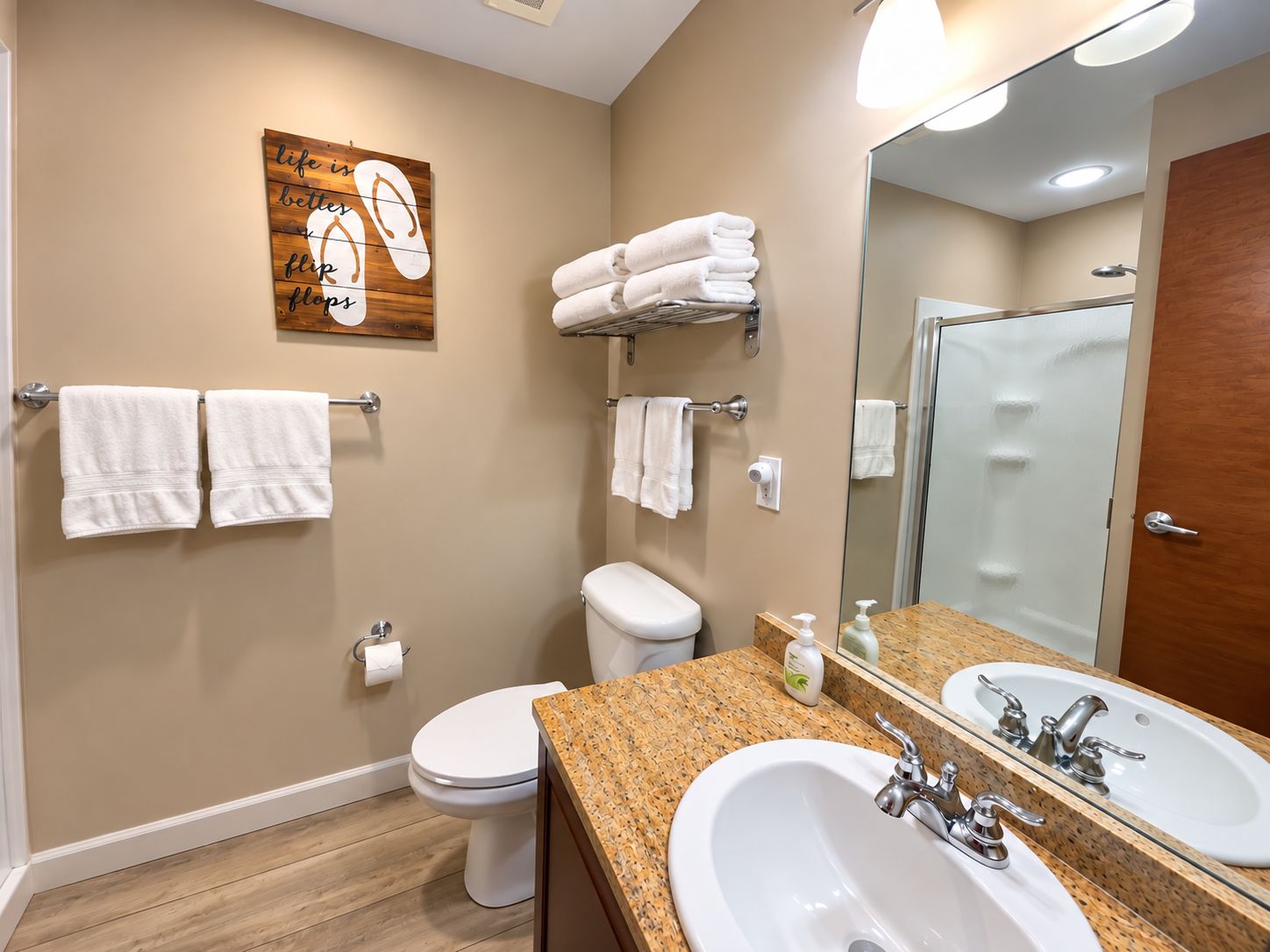 Een badkamer met toilet, wastafel en een handdoekrek met handdoeken.