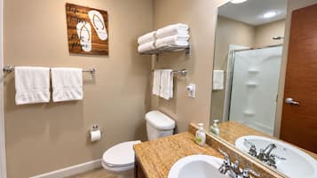 Een badkamer met toilet, wastafel en een handdoekrek met handdoeken.