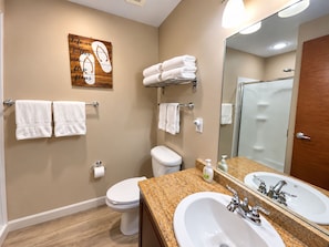 Een badkamer met toilet, wastafel en een handdoekrek met handdoeken.