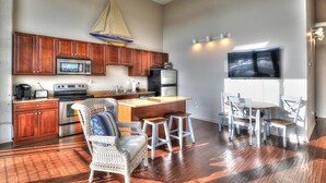 A spacious kitchen with wooden cabinets, a large island, and a dining area with white chairs. - Upgrade Your Stay...On Sandusky Bay! (Sandusky)