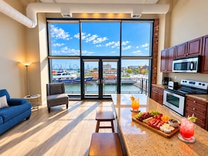 A modern kitchen with a large island, a dining area with a blue sofa, and a view of a marina through large windows.
