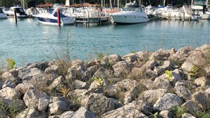 A marina with boats docked, surrounded by large rocks and sparse vegetation. - BeachFrontRental-Tennis court&playground directly across the street!DogsWelcome (Elk Rapids)