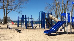 A playground with a slide, climbing structures, and benches. - BeachFrontRental-Tennis court&playground directly across the street!DogsWelcome (Elk Rapids)