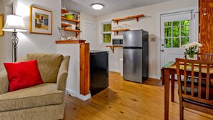 A compact living space with a kitchenette, a dining area, and a seating area with a sofa and a chair.