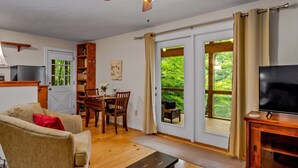 A living room with a sofa, a TV, a wooden coffee table, and a dining area with a table and chairs.