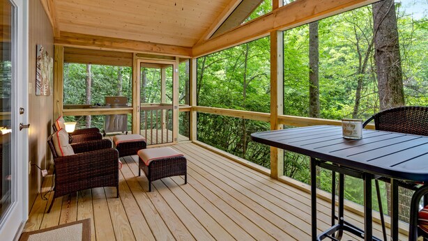 A covered outdoor deck with wicker furniture, a table, and a ceiling fan.