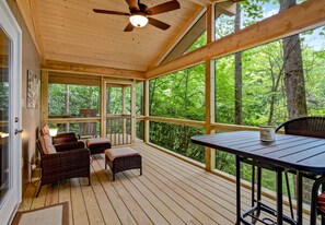 A covered outdoor deck with wicker furniture, a table, and a ceiling fan. - Romantic Rural Retreat/Hot tub/Fishing/Pond view/Woods/Private (Arden)