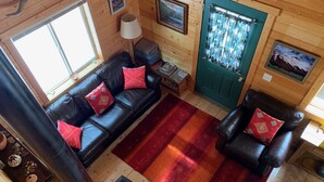 A cozy cabin interior with a black leather sofa, a red and orange striped rug, and a wood-burning stove. - Pristine Cabin near Craig...  Fish, or just Relax (Cascade)