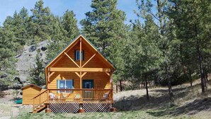 A two-story log cabin with a balcony, surrounded by pine trees. - Pristine Cabin near Craig...  Fish, or just Relax (Cascade)